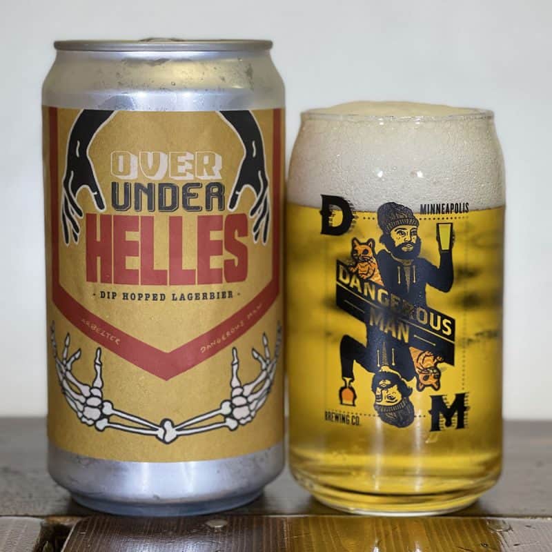 Pint glass of beer next to a crowler of Dangerous Man Brewing & Arbeiter Brewing Over Under Helles.