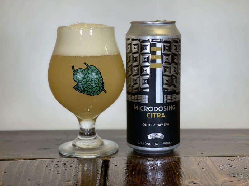 Snifter of beer sitting next to a can of BlackStack Brewing Microdosing: Citra Once A Day IPA.