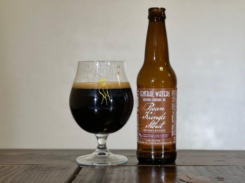 Snifter glass of beer and a bottle of Central Waters Brewing Pecan Kringle Stout.