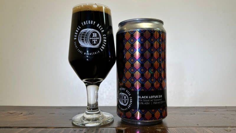 Snifter glass of dark beer next to a crowler of Barrel Theroy Brewing Black Lotus 2.0.