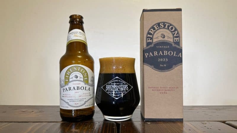 Bottle of Firestone Walker Brewing Parabola 2023 next to a box the beer came in, with a glass of dark beer sitting in between them.