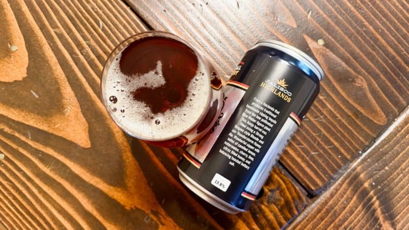 Top-down look at a snifter of Town Hall Brewery Jalisco Highlands next to an empty crowler on a wood table.